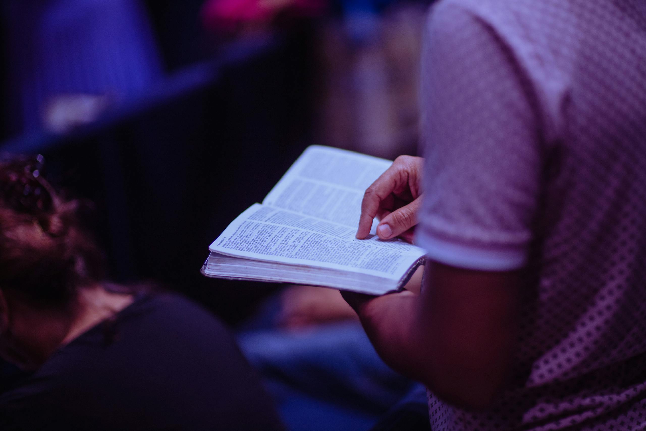Betania - Calgary | A focused moment of a person engaged in reading a Bible inside a church.